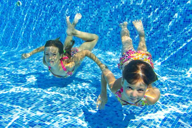 Kids playing underwater in a clean pool